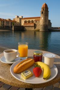 a plate of food with fruit and juice on a table at Résidence du Soleil & Spa - Collioure in Collioure