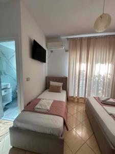a bedroom with two beds and a television in it at Oliver Studios in Ksamil