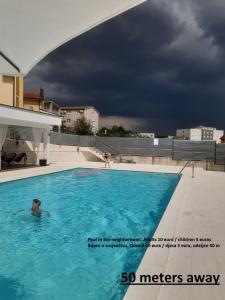 a man in a swimming pool under a cloudy sky at Pansion Ivan in Međugorje