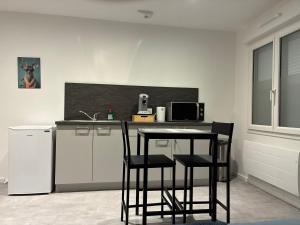 a kitchen with two chairs and a table and a refrigerator at Appart orange 25 m2 neuf RDC in Sainte-Marie-aux-Chênes