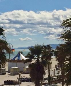 a view of a beach with a tent and palm trees at Appartement Canet in Canet-en-Roussillon