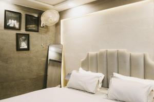 a bedroom with a bed with white sheets and pillows at Grey Courtyard Entire Studio Taj Mahal Parking 3KM in Agra