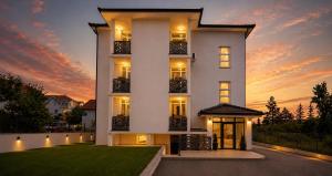 a white house with a sunset in the background at Park and Fly Belgrade Airport Apartments in Surčin