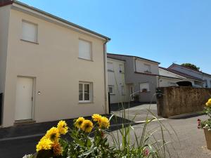 a row of houses with yellow flowers in a yard at Appart orange 25 m2 neuf RDC in Sainte-Marie-aux-Chênes