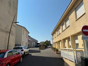 a street with two cars parked next to a building at Appart orange 25 m2 neuf RDC in Sainte-Marie-aux-Chênes