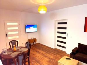 a living room with a table and a television on a wall at EBRAM II Apartments Görlitz in Görlitz