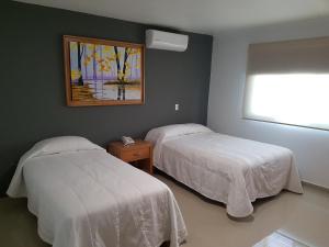 a bedroom with two beds and a painting on the wall at Casa RyS Hotel in Ocotlán