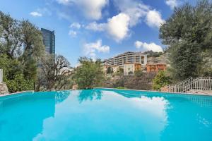 a large blue swimming pool with buildings in the background at Monte Carlo Monaco Border, Swimming Pool, Parking, See View, Terrace in Beausoleil