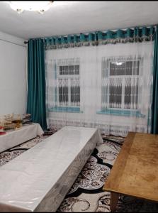 a room with a bed and a window with green curtains at Keremet house in Barskoon