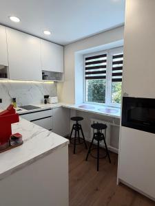 a kitchen with white cabinets and a window and stools at AC Central Station apartments in Daugavpils