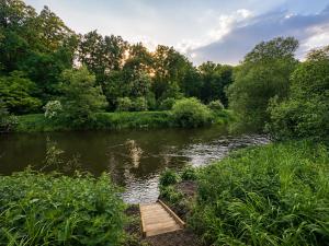 a wooden bridge over a river with trees at maringotka Hedvika glamping in Pašice