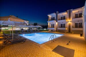 a swimming pool in front of a building at night at Porto Dionysos in Ofrínion