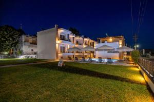 a large white building with tables and umbrellas at night at Porto Dionysos in Ofrínion