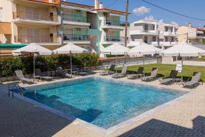 a swimming pool with chairs and umbrellas in front of a building at Porto Dionysos in Ofrínion