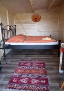 a bed in a wooden room with a rug at Cottage in Remízek in Havlíčkŭv Brod