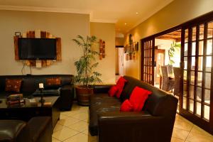 a living room with a black leather couch and red pillows at Skilpadvlei Cottage and Studio's in Velddrif