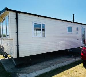 a white tiny house sitting in a parking lot at 22 seabreeze holiday park in Hemsby