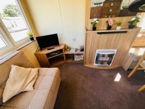 a living room with a couch and a television at 22 seabreeze holiday park in Hemsby +5 photos