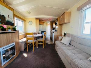 a living room with a couch and a table and a kitchen at 22 seabreeze holiday park in Hemsby