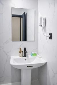 a white bathroom with a sink and a mirror at Airport Garden hotel in Pʼarakʼar