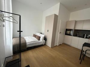 a white bedroom with a bed and a kitchen at Apartament Mini Stary Sącz in Stary Sącz