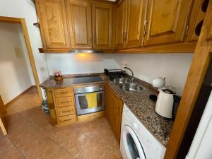 a kitchen with wooden cabinets and a sink and a dishwasher at Apartamento Airoso em Miranda in Miranda do Douro