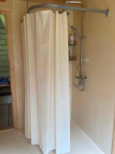 a shower with a white shower curtain in a bathroom at Kenu Saunamaja in Haapsalu