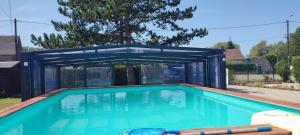 a swimming pool in a house with a blue structure at Les étoiles de la Baie in Lanchères