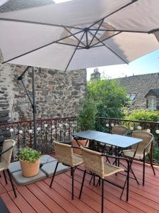 a table and chairs with an umbrella on a deck at Hôtel Restaurant Le Beffroi in Salers