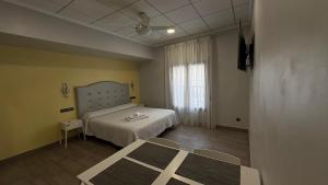 a bedroom with a bed and a table and a window at Alojamientos Templete in Caravaca de la Cruz