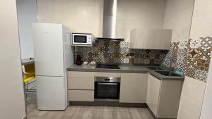 a kitchen with a white refrigerator and a microwave at Alojamientos Templete in Caravaca de la Cruz