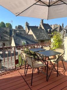 a table and chairs on a deck with an umbrella at Hôtel Restaurant Le Beffroi in Salers