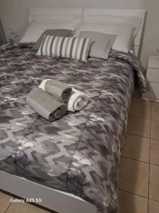 a bed with camo sheets and towels on it at Appartamento Catini 67 in Civitavecchia