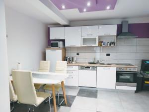 a kitchen with white cabinets and a table and chairs at Apartman Brzović in Omiš
