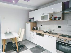 a kitchen with white cabinets and a table and a sink at Apartman Brzović in Omiš