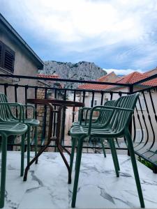 three green chairs and a table on a balcony at Apartman Brzović in Omiš