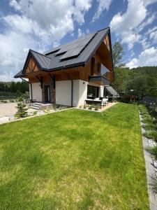 a house with a metal roof on a lawn at Osada pod Sokolicą in Krościenko