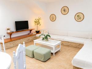 a living room with a white couch and a tv at Wine & Vineyard Retreat Emarmene in Koskinou