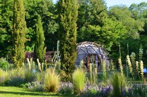 a greenhouse in a garden with flowers and trees at Ô Pays Des Bois - Bulles et logements insolites en pleine nature - Adults Only in Parmilieu