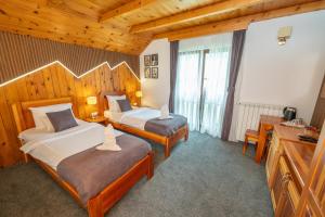 two beds in a hotel room with wooden ceilings at Rooms and apartmants Mirovic in Kolašin