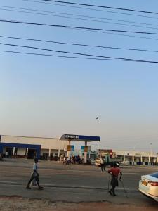two people crossing a street in front of a gas station at KIGALI E6 APARTMENTs RESORTS in Kigali