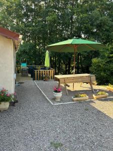 a picnic table with a green umbrella and flowers at Gite du Tacot 21 in Saulieu