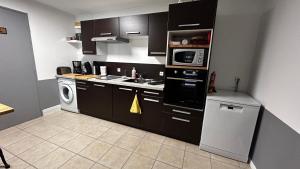 a kitchen with black cabinets and a washer and dryer at Gite du Tacot 21 in Saulieu