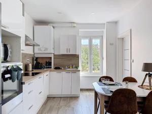 a kitchen with white cabinets and a table with chairs at EM LIFE COLMAR in Colmar