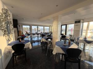 a restaurant with tables and chairs and windows at Water's Edge Hotel in Birżebbuġa
