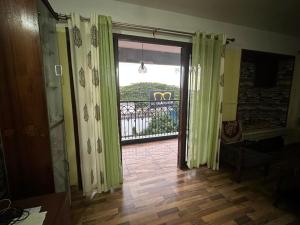 an open door to a balcony with green curtains at ChriSeph in Kottayam