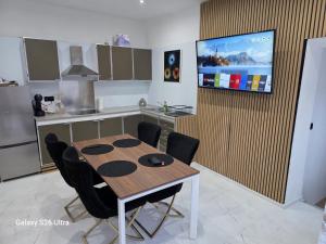 a kitchen with a table and a tv on a wall at Fleurus House in Fleurus