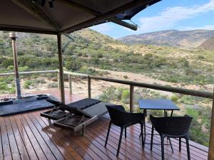 a porch with chairs and a table and a view at Oudemuur Glamping in Montagu
