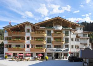 a large building with red umbrellas in a parking lot at Hotel Jägerhof in Gerlos