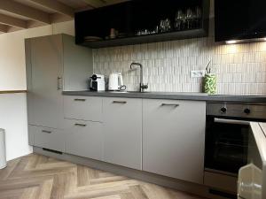 a kitchen with white cabinets and black appliances at De Kustwacht in Warmenhuizen